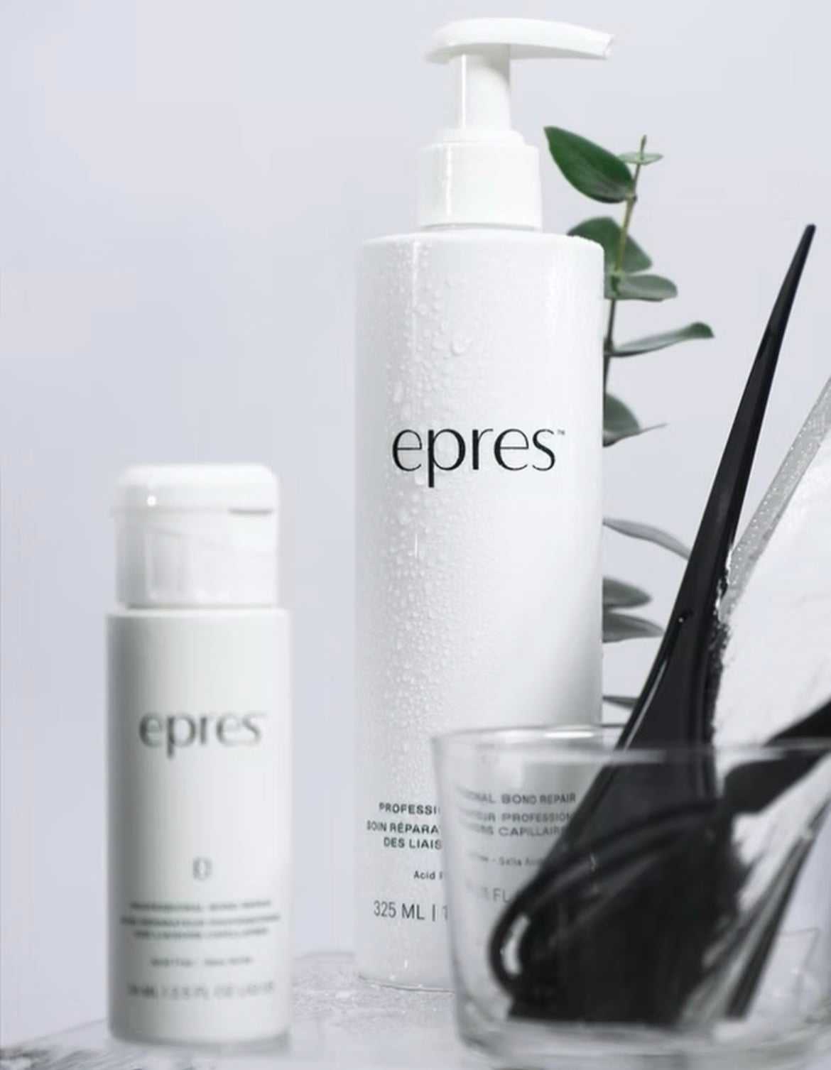 Two Epres skincare bottles with fresh green leaves, on a white background.