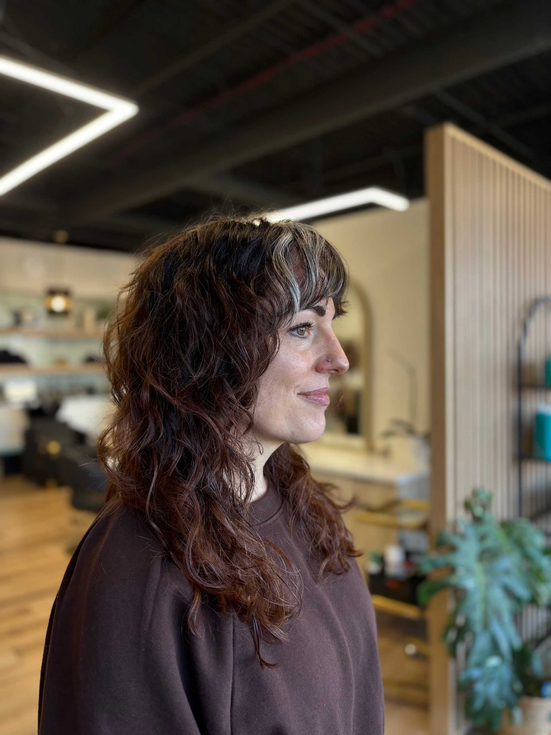 Person with curly hair in a salon, looking to the right.